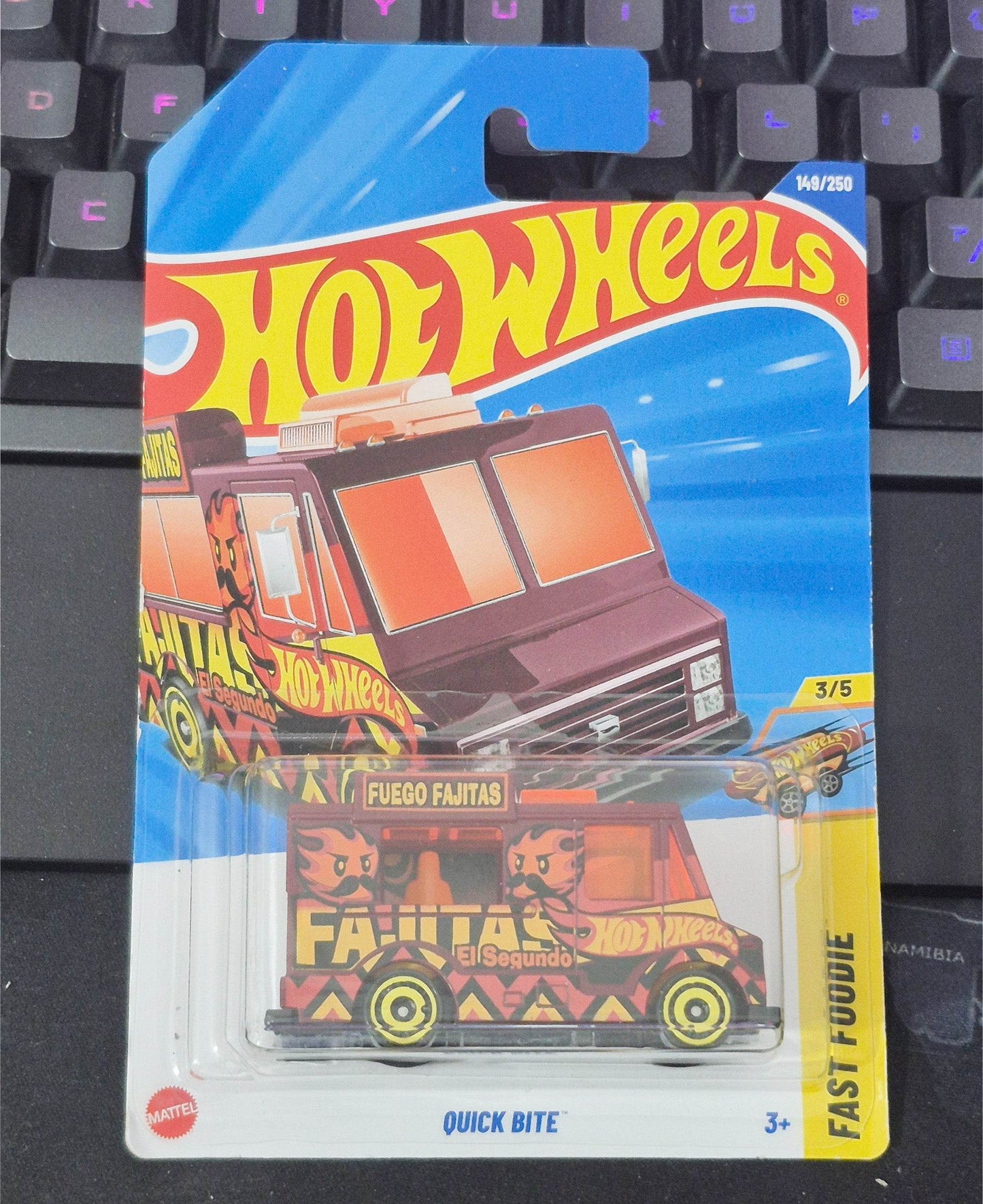 Hot Wheels toy car in packaging on a keyboard
