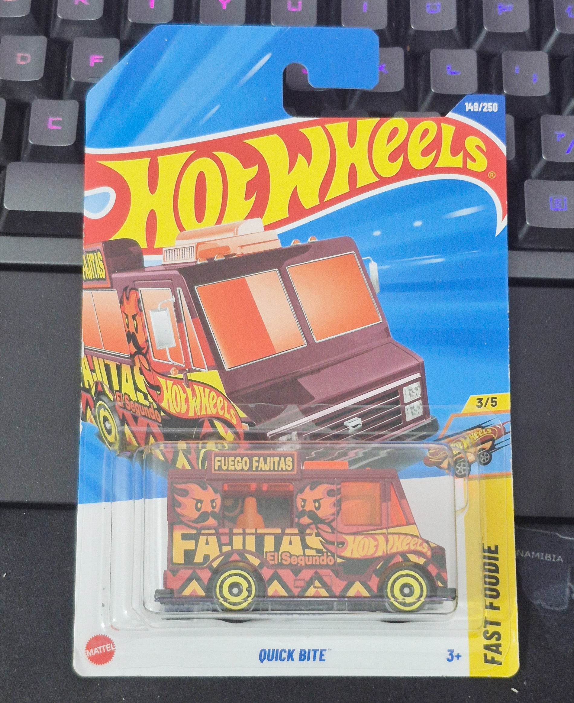 Hot Wheels toy car in packaging on a keyboard